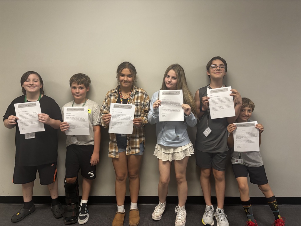 six students standing holding a piece of paper