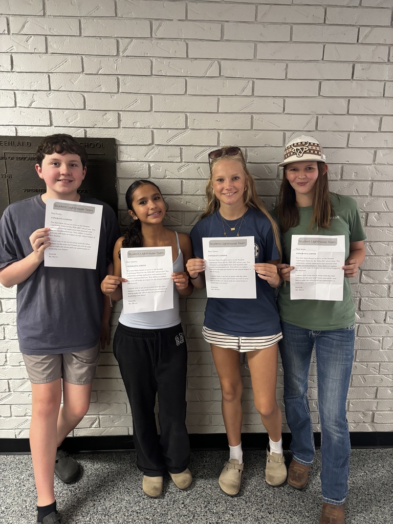 four students standing holding a piece of paper