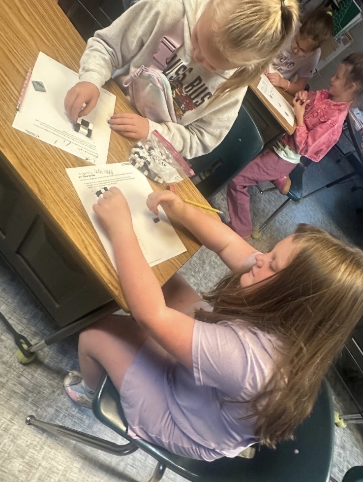 Four  kids at a table with cubes and paper