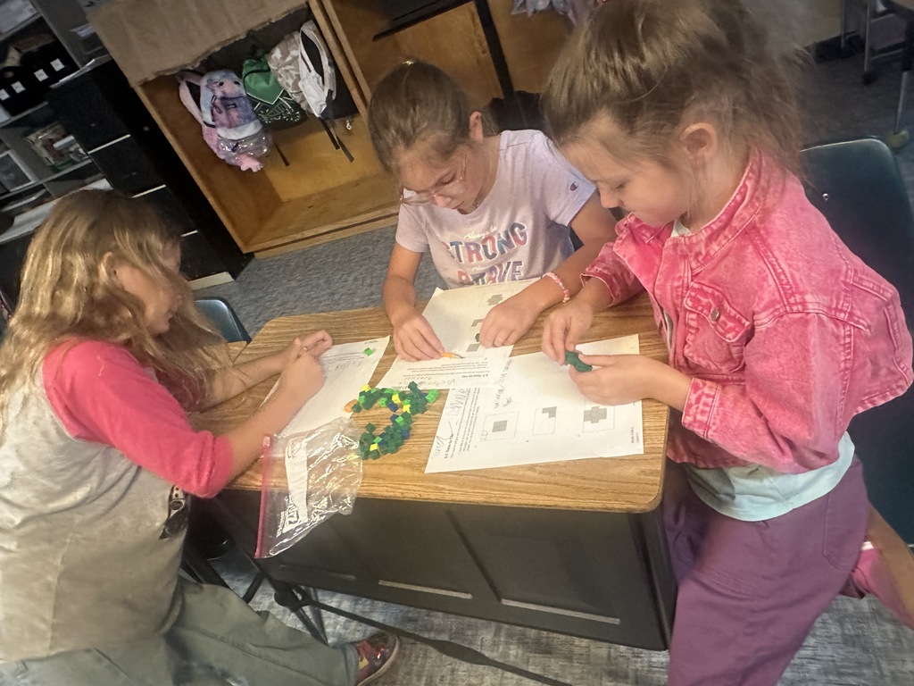 Three kids at a table with cubes and paper