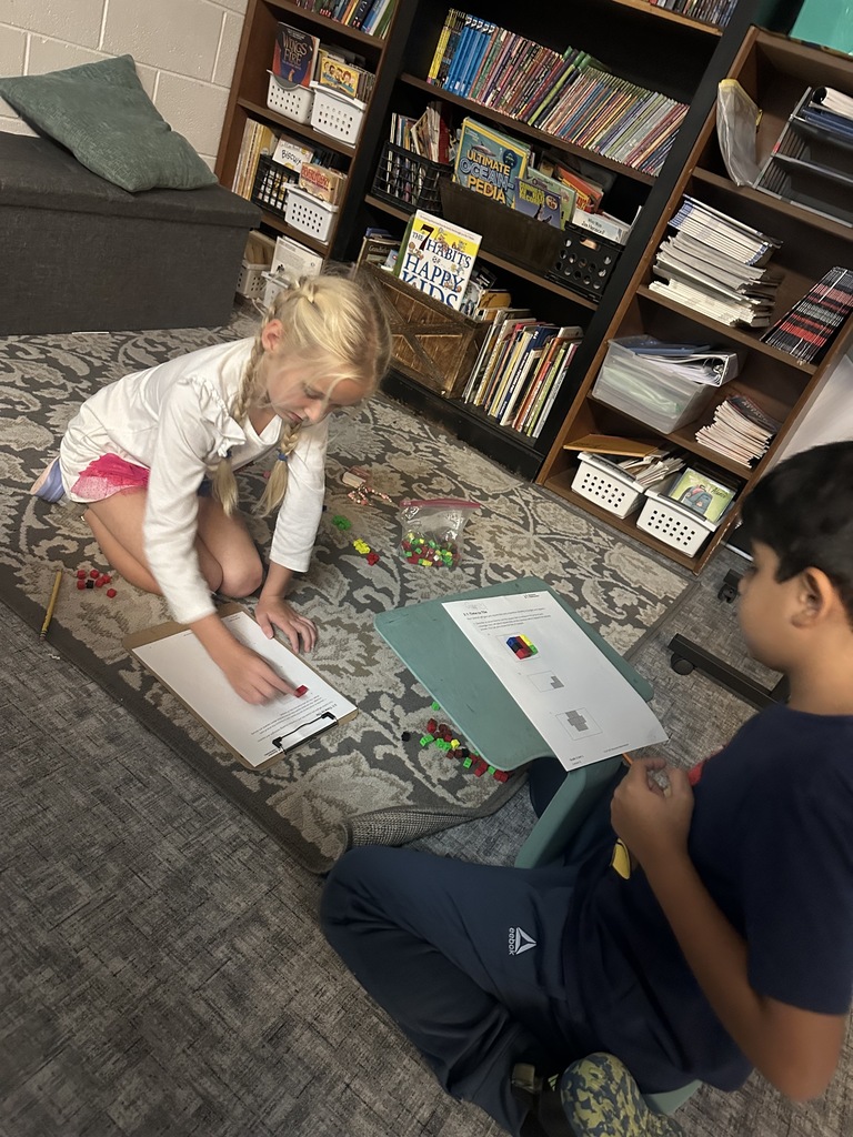 Two kids at a table with cubes and paper
