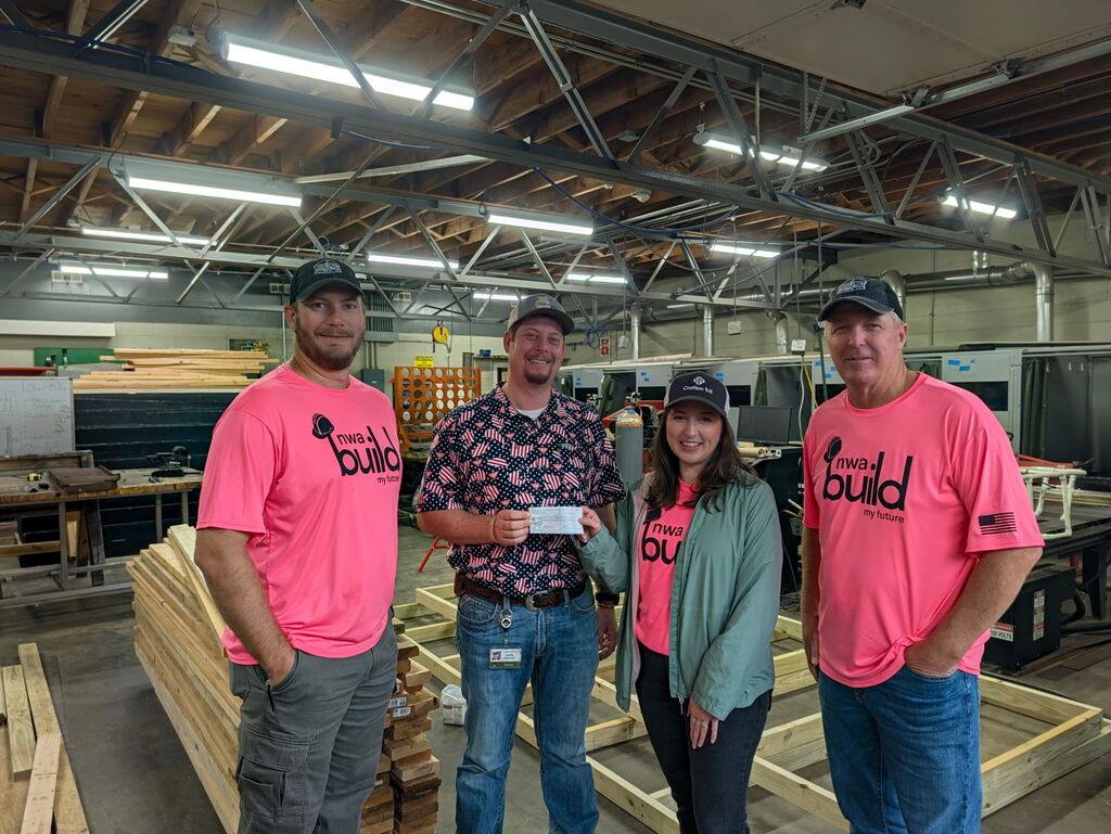 4 people posing holding a check with boards in the background
