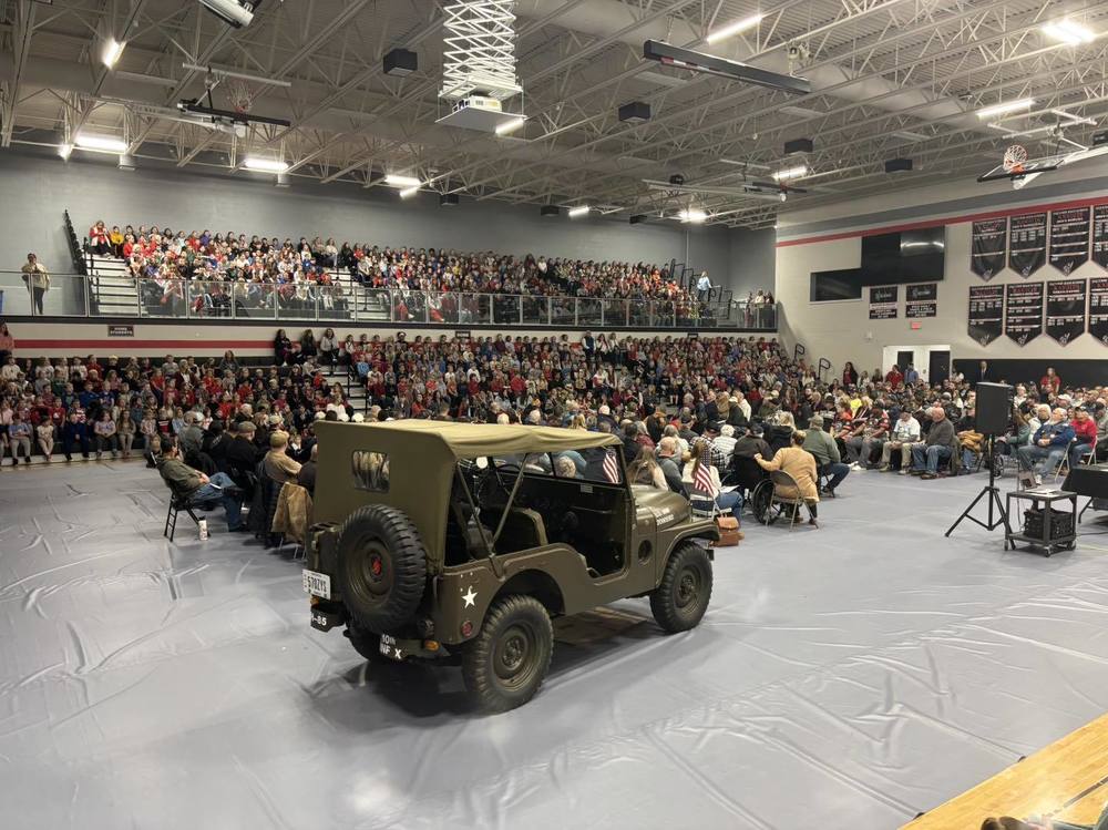 Gym full of hundreds of students and veterans and an army jeep