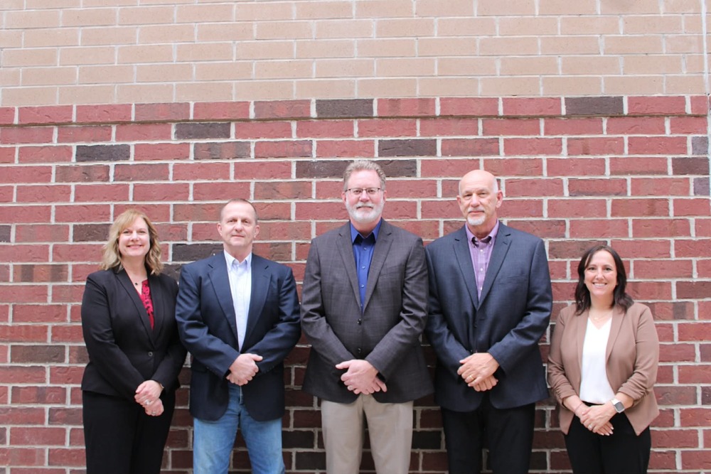 Group of board members stnading on a brick wall