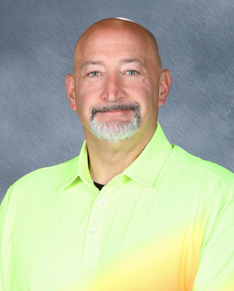 Bald Man with bright yellow shirts smiling.