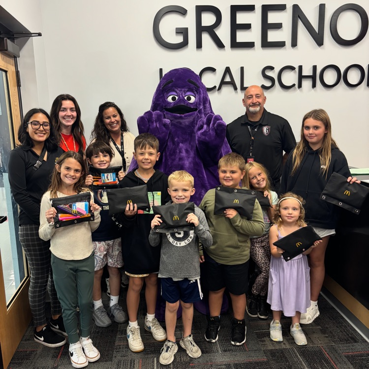 group of students and adults with purple mascot from McDonald’s holding school 