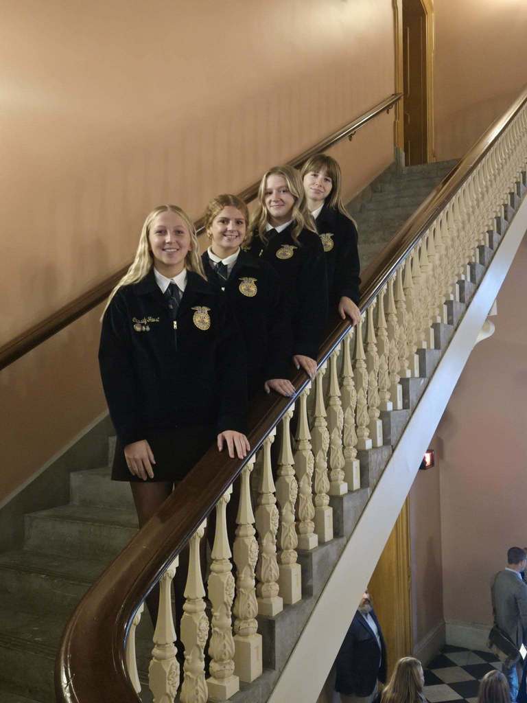 Students in blue jackets standing on staircase