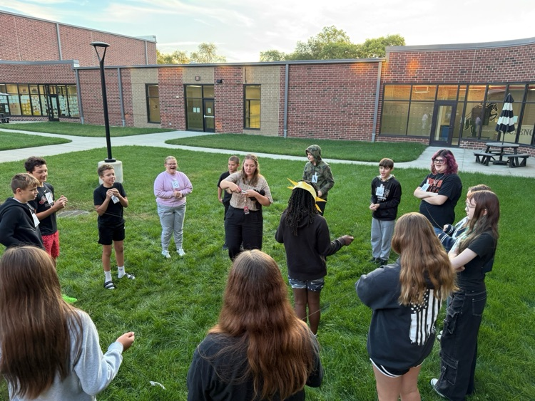 students in a circle hold yarn