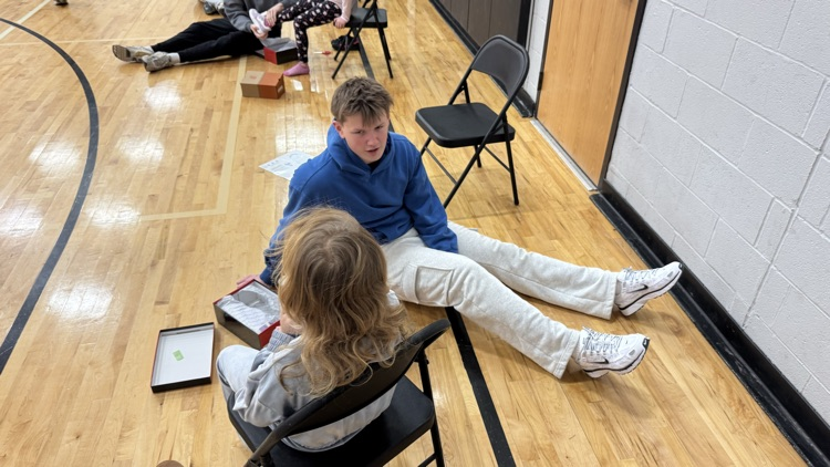 old student helping younger student try on shoes