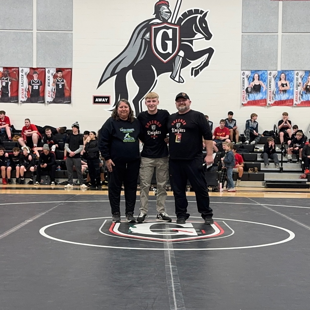 2 adults and student standing in the middle of a wrestling ring