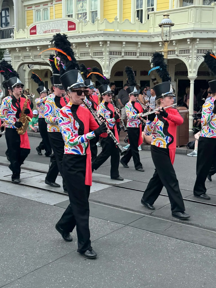 marching band marching in street between building