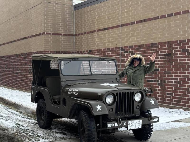 veteran with Army Jeep outside in front of brick building