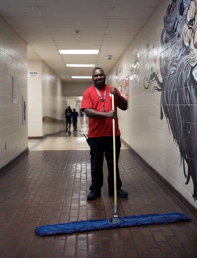 Custodian sweeping hallway