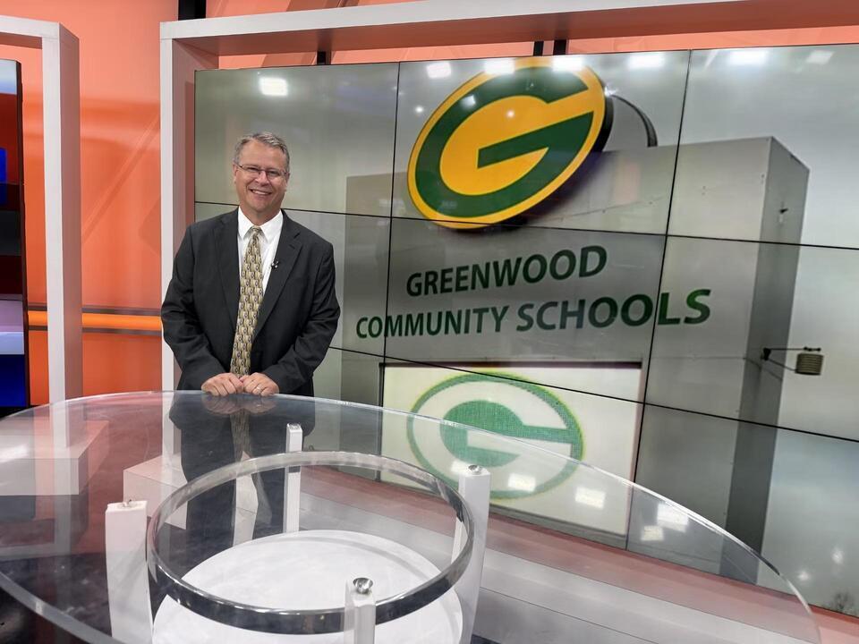 Dr. Terhune apperance on Wish-TV's Morning Bell Segment, stands in front of a video display of the Greenwood Community Schools sign.