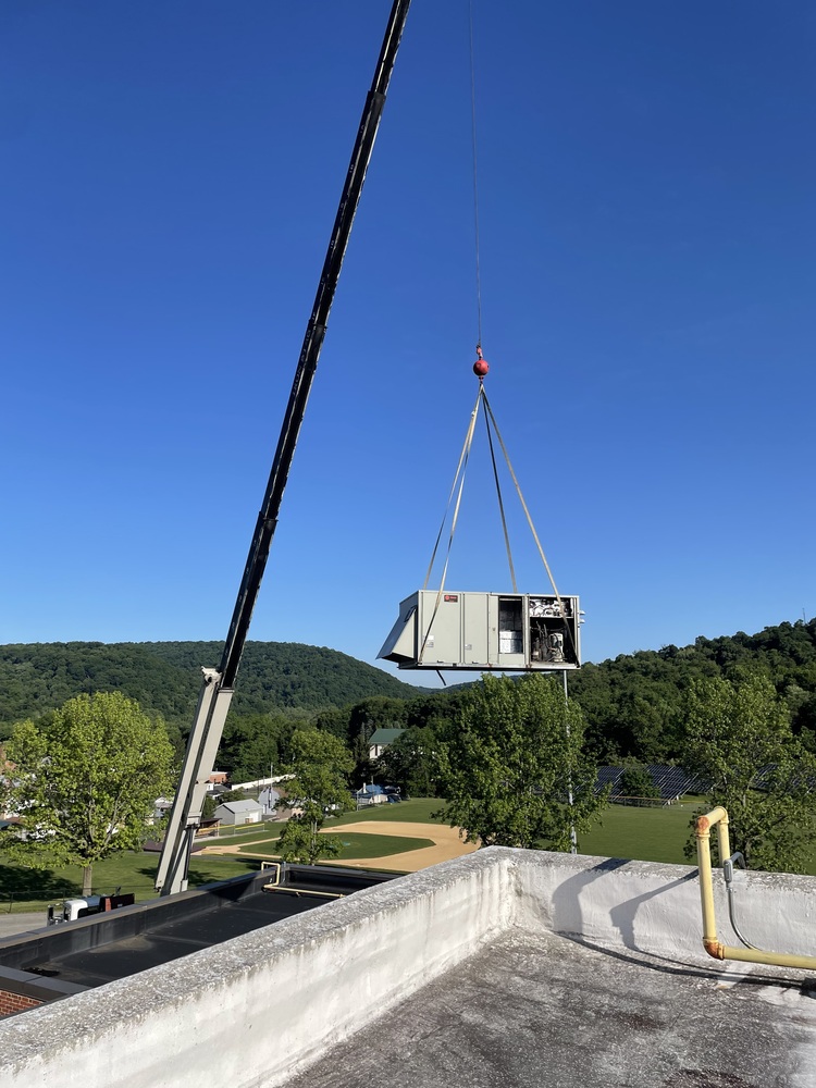 Crane lifting a rooftop HVAC Unit