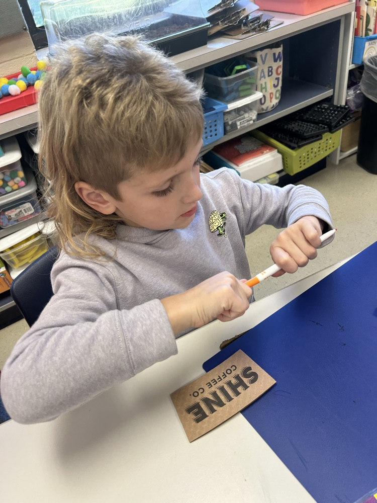 student holding a marker about to color on a shine coffee company hot coffee sleeve