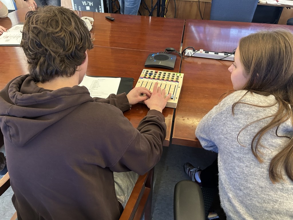 Students practicing using a soundboard to mix music and vocals.