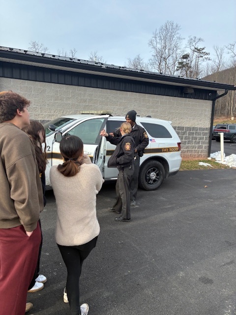Troopers show students the inside of a police car and explain how this tool is paramount to completing their jobs.