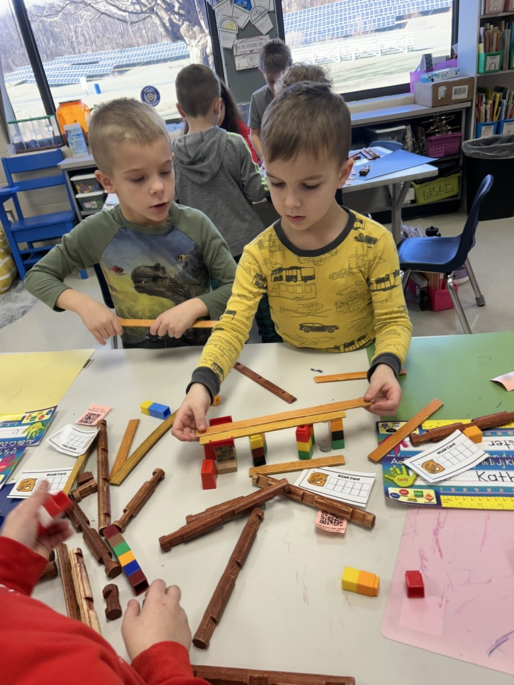 two students working to create a bridge with snap cubes and wood flats 