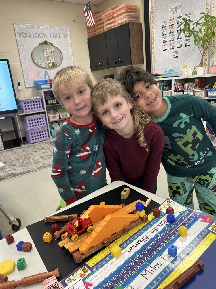 three students smile with their version of a suspension bridge 