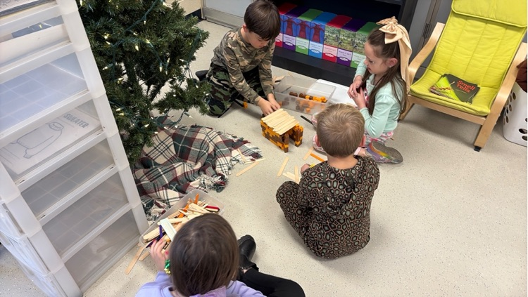 four students use popsicle sticks and snap cubes to build a bridge 