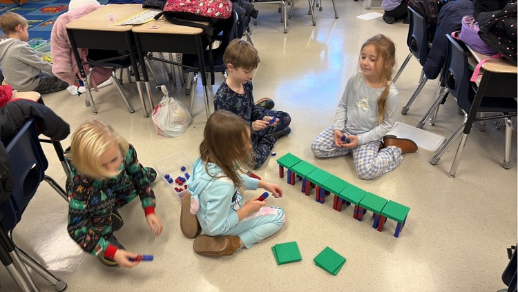 four students use hundreds blocks and snap cubes to create a bridge 