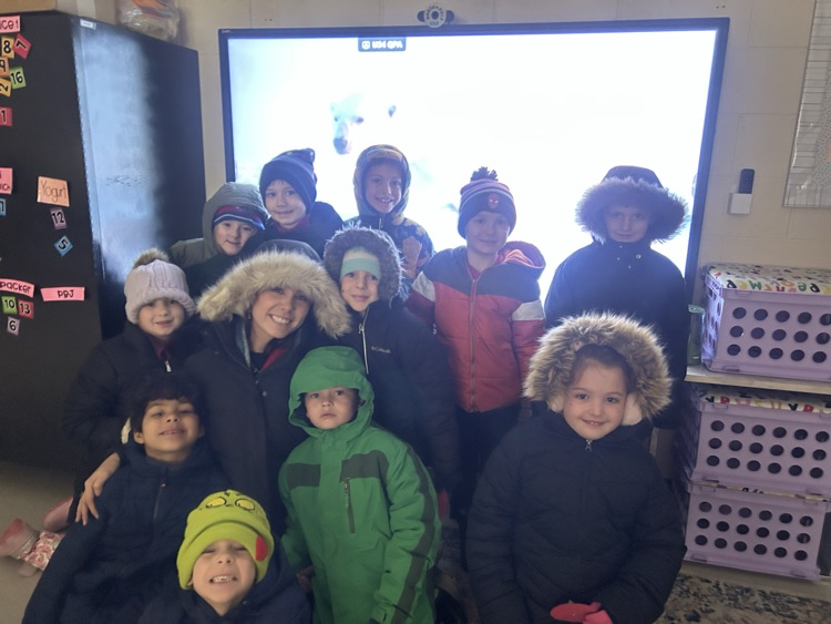 students smiling with their teacher bundled up for a nature walk 