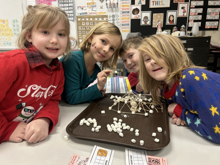 4 students smile with their clay made arctic animal in an igloo made out of popsicle sticks and marshmallows 