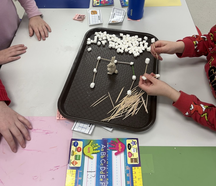 students working on a tray to create an igloo out of popsicle sticks and marshmallows 