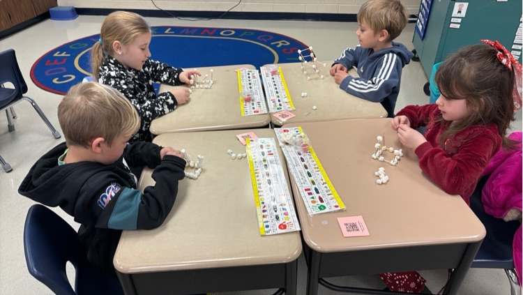 four students work to create individual igloos out of marshmallows and toothpicks 