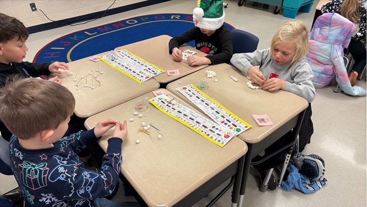 four students work to create individual igloos out of marshmallows and toothpicks 
