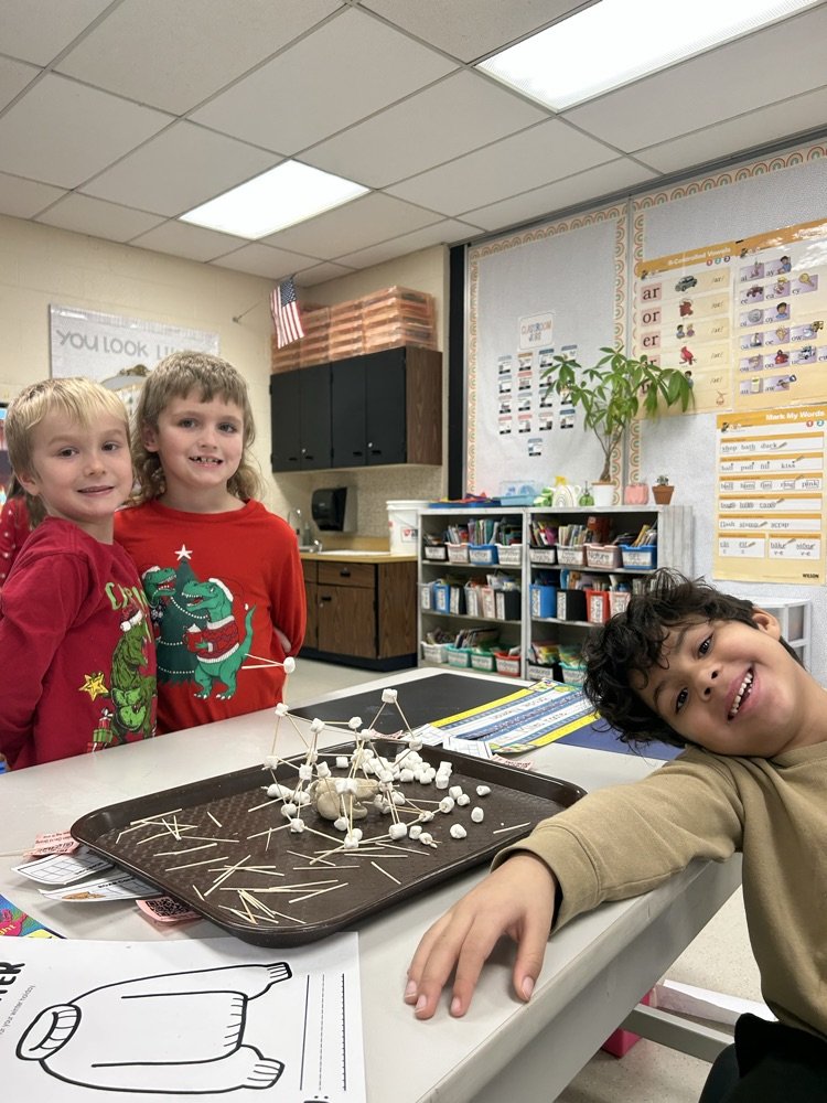 three students smile for a photo with their finished igloo and clay made polar bear 