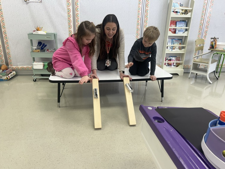 2 students and their teacher test their bobsleighs on a wooden ramp 