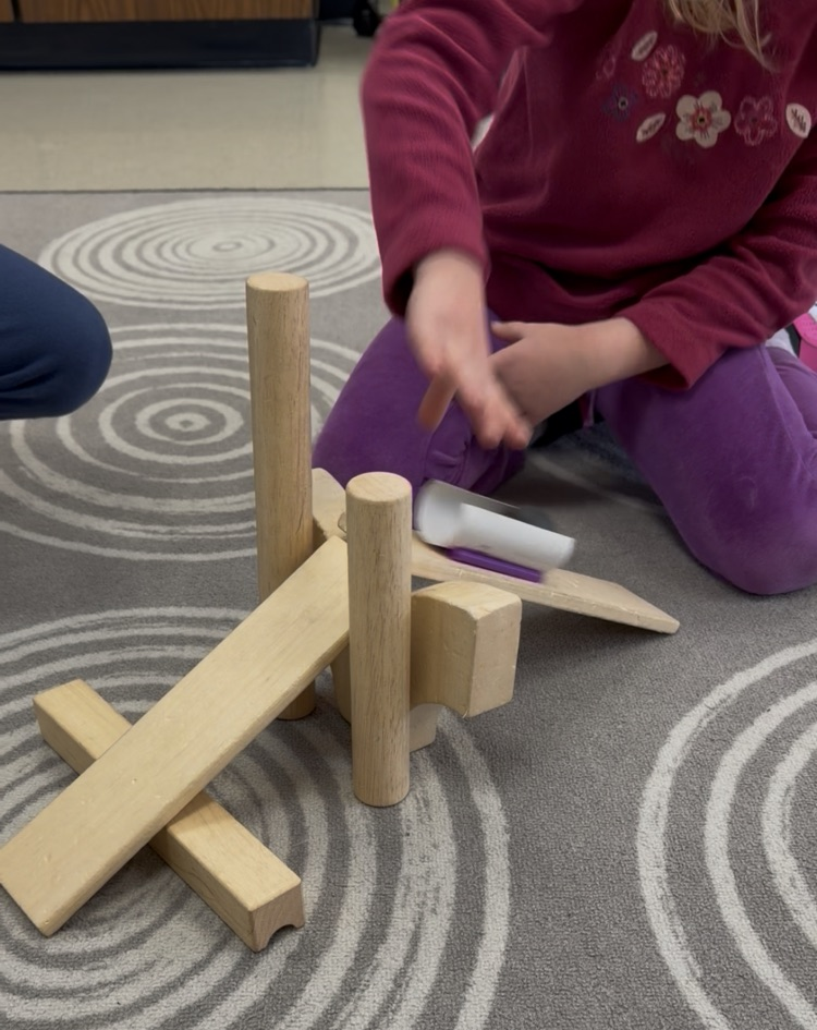 a students hands are seen testing a bobsleigh creation on wooden blocks 