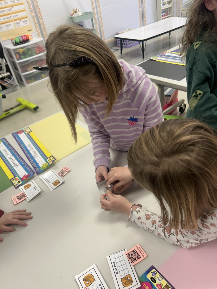 two students work to wrap foil around their toilet paper roll to make a smoother bottom on their bobsleigh 