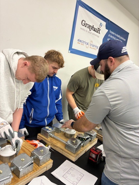 Jacob Anderson and Brayden Beneito get some instruction as they prepare to test their hands on project at IBEW.