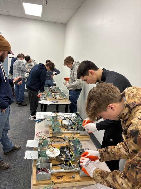 Dylan Womer, Bronson Moyer, Corbin Campbell, and Tyler Moffitt work on a hands on electrical simulation at IBEW. 