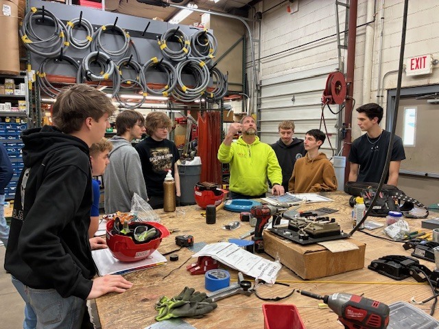 Secco employee shows our students pictures of different projects that were fabricated in the shop and then installed at a job site.