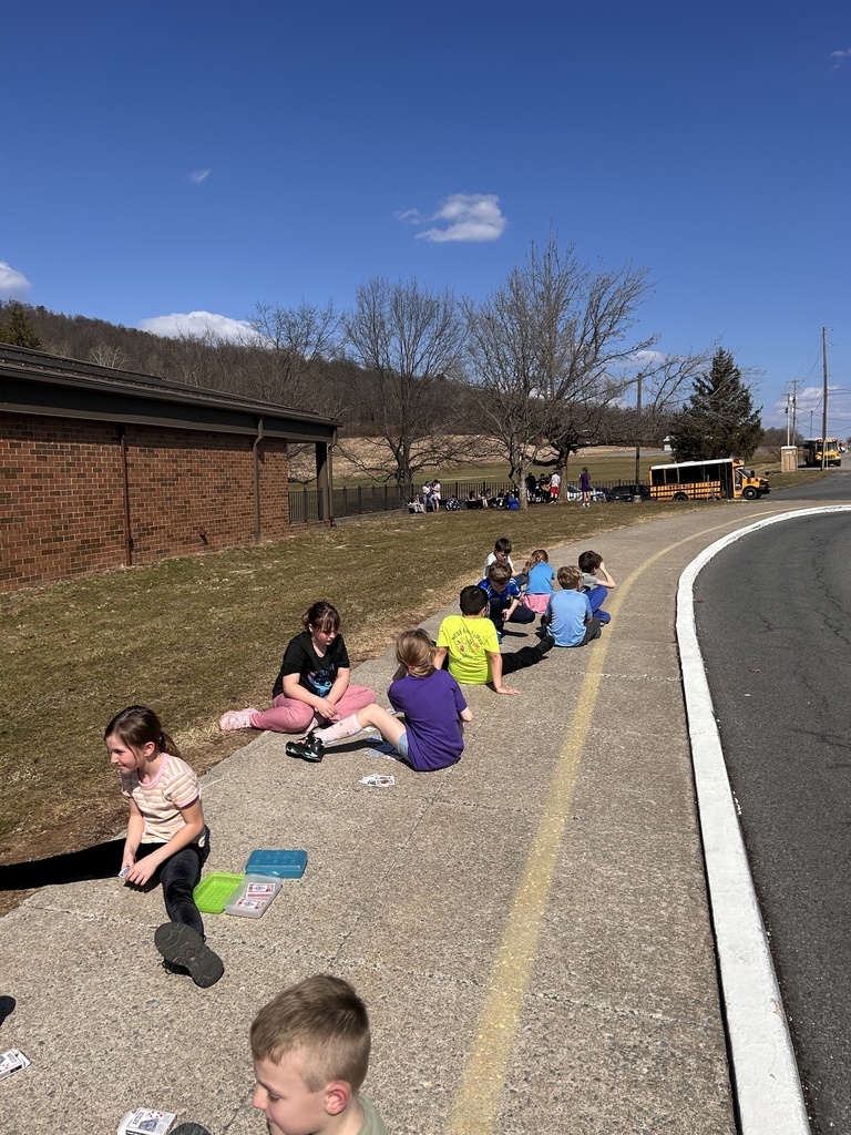 Students sitting outside on the sidewalk practicing math facts