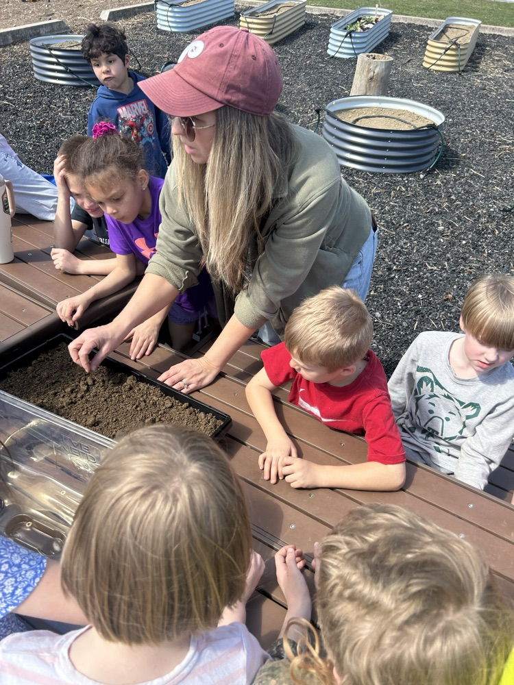 students plant within a windowsill greenhouse  