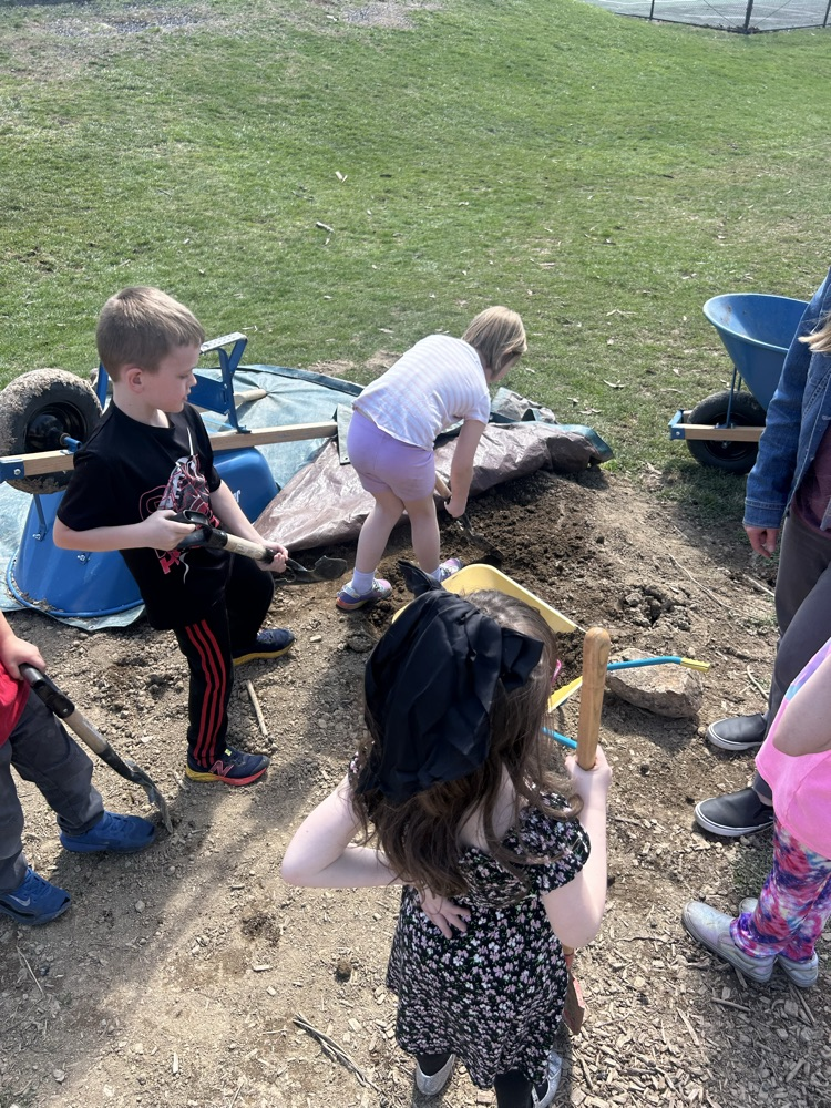 student use shovels to dig at organic material to gather for planting 