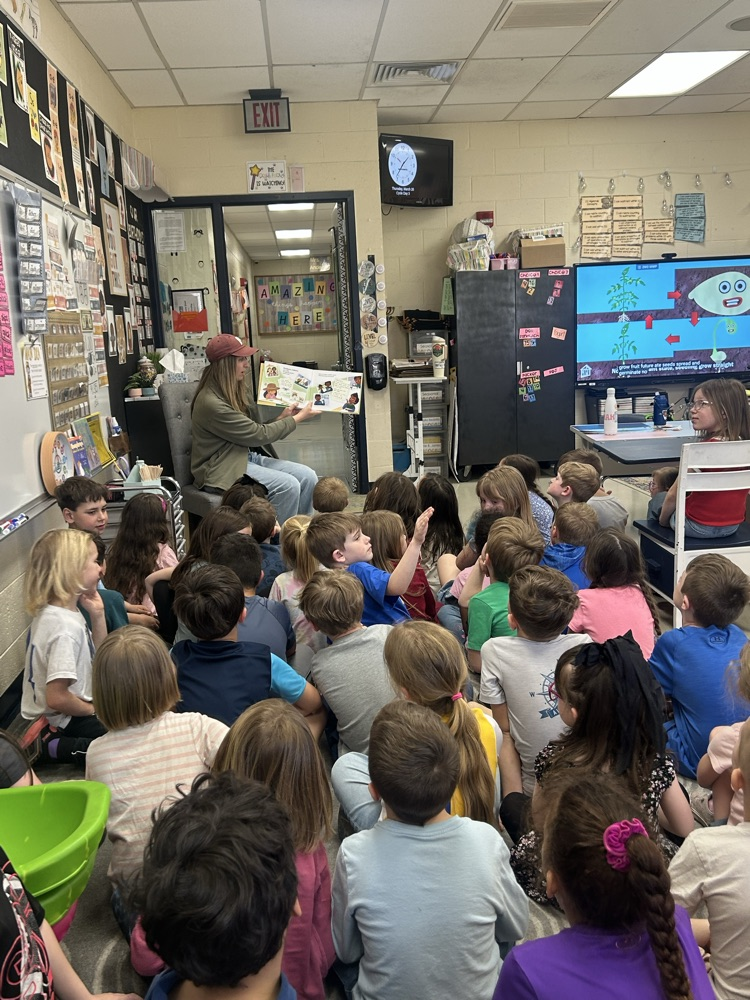 teacher reads a story about indoor and outdoor gardening needs while the tomato life cycle is shown on the smart board 