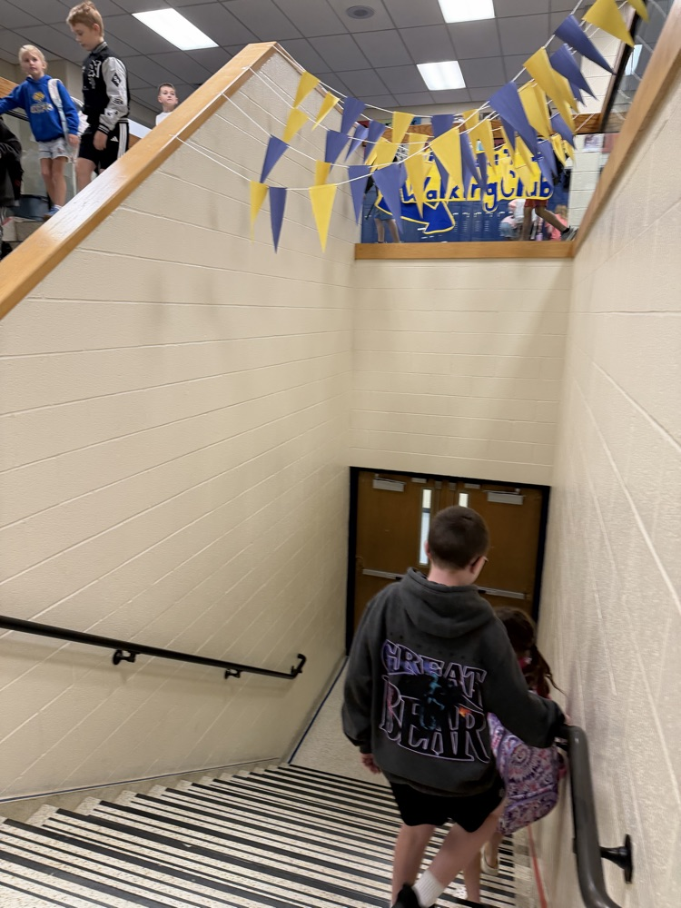 students walking down hallway stairs under a yellow and blue banner