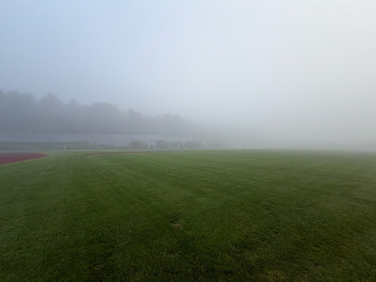 students walking the track behind fog