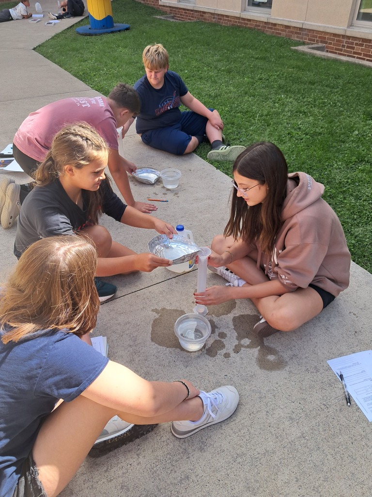 student pouring water into a graduated cylinder