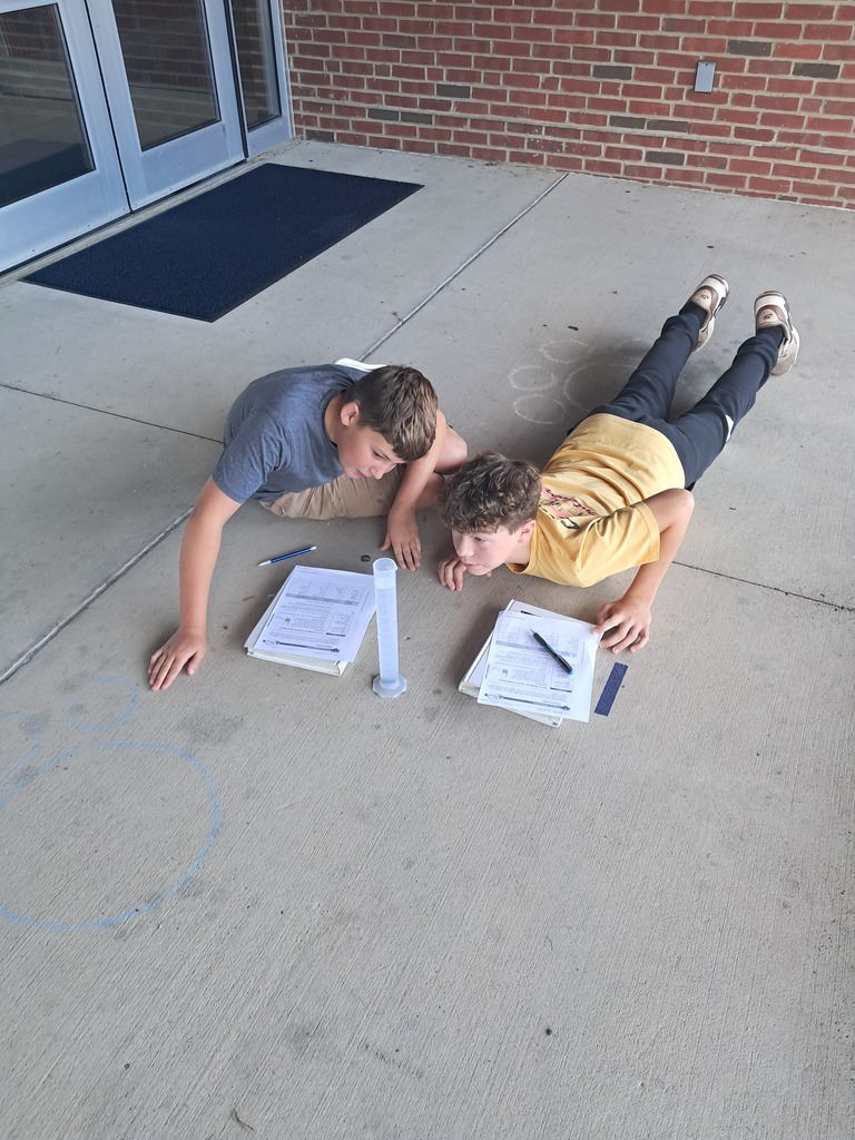 students measuring the amount of water in a graduated cylinder