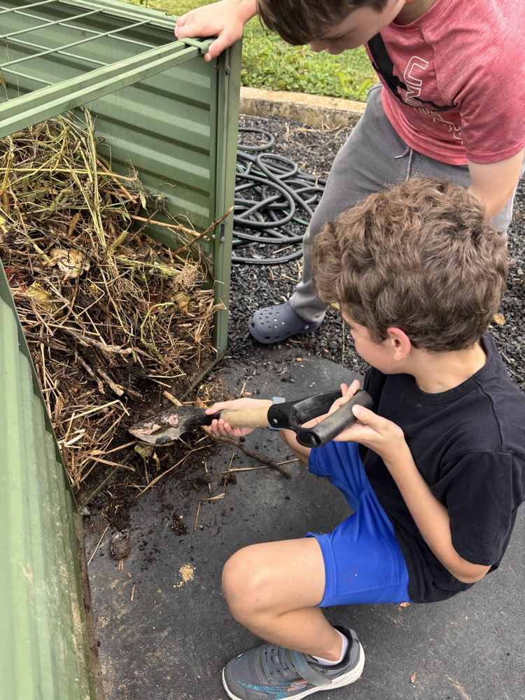 student digging in compost for soil