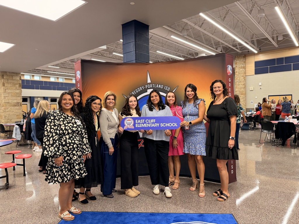 A group of women standing together in a retail store, holding a sign that reads "East Cliff elementary".