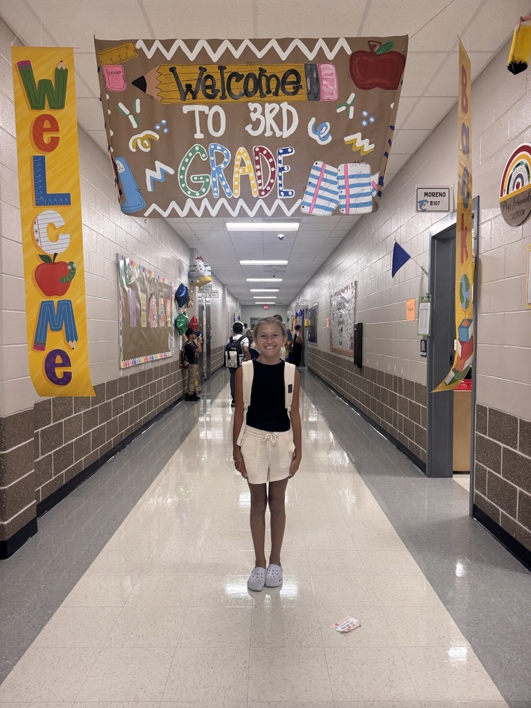 Hallway decorated with "Welcome to 3rd Grade" banner, colorful artwork, and a student standing in the center.