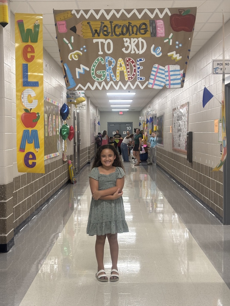 Welcome to 3rd grade hallway with colorful signs, a smiling student standing in the middle.